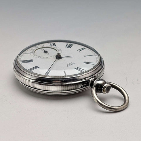 Reloj de bolsillo inglés antiguo de 1864, John Bennett, de cuerda con llave, caja de plata, esfera abierta, en buen estado de funcionamiento.