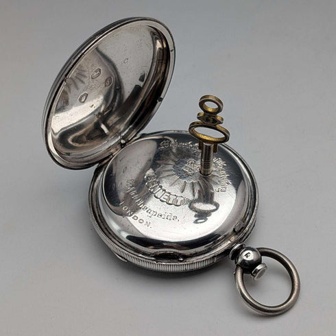 Reloj de bolsillo inglés antiguo de 1864, John Bennett, de cuerda con llave, caja de plata, esfera abierta, en buen estado de funcionamiento.