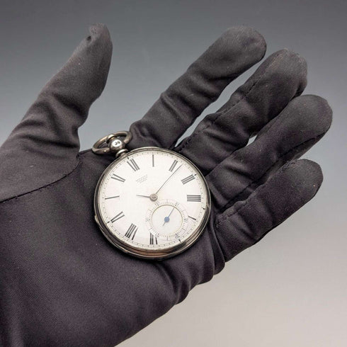 Reloj de bolsillo inglés antiguo de 1864, John Bennett, de cuerda con llave, caja de plata, esfera abierta, en buen estado de funcionamiento.
